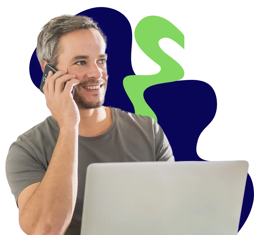 Happy man on phone in front of laptop making an NDIS referral